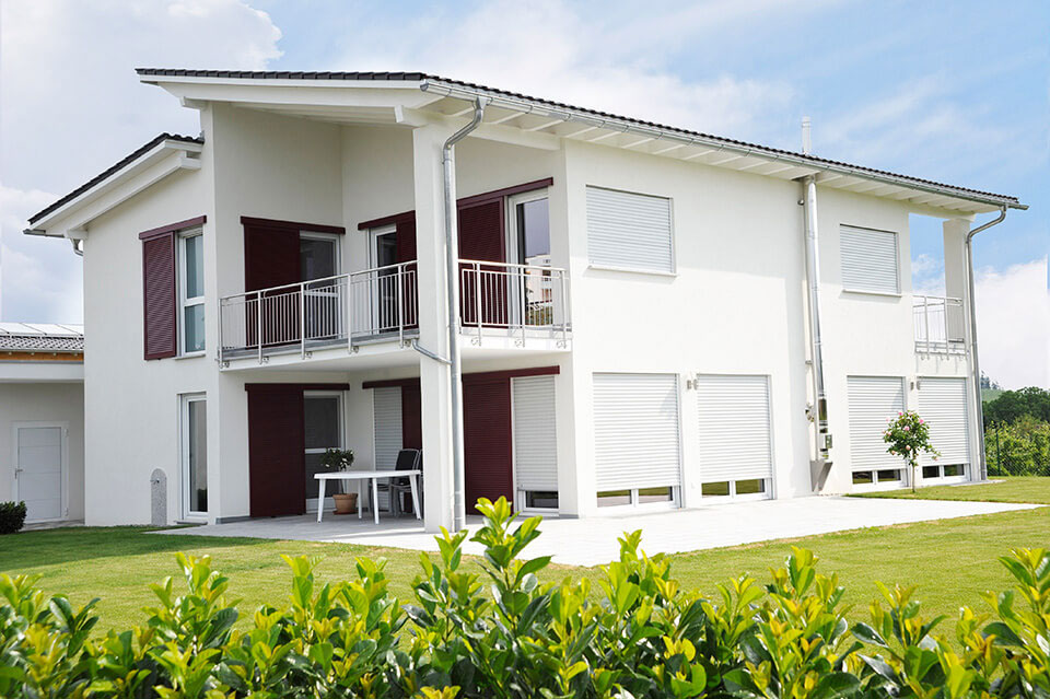 Einfamilienhaus mit weißen Fenstern und Jalousien.